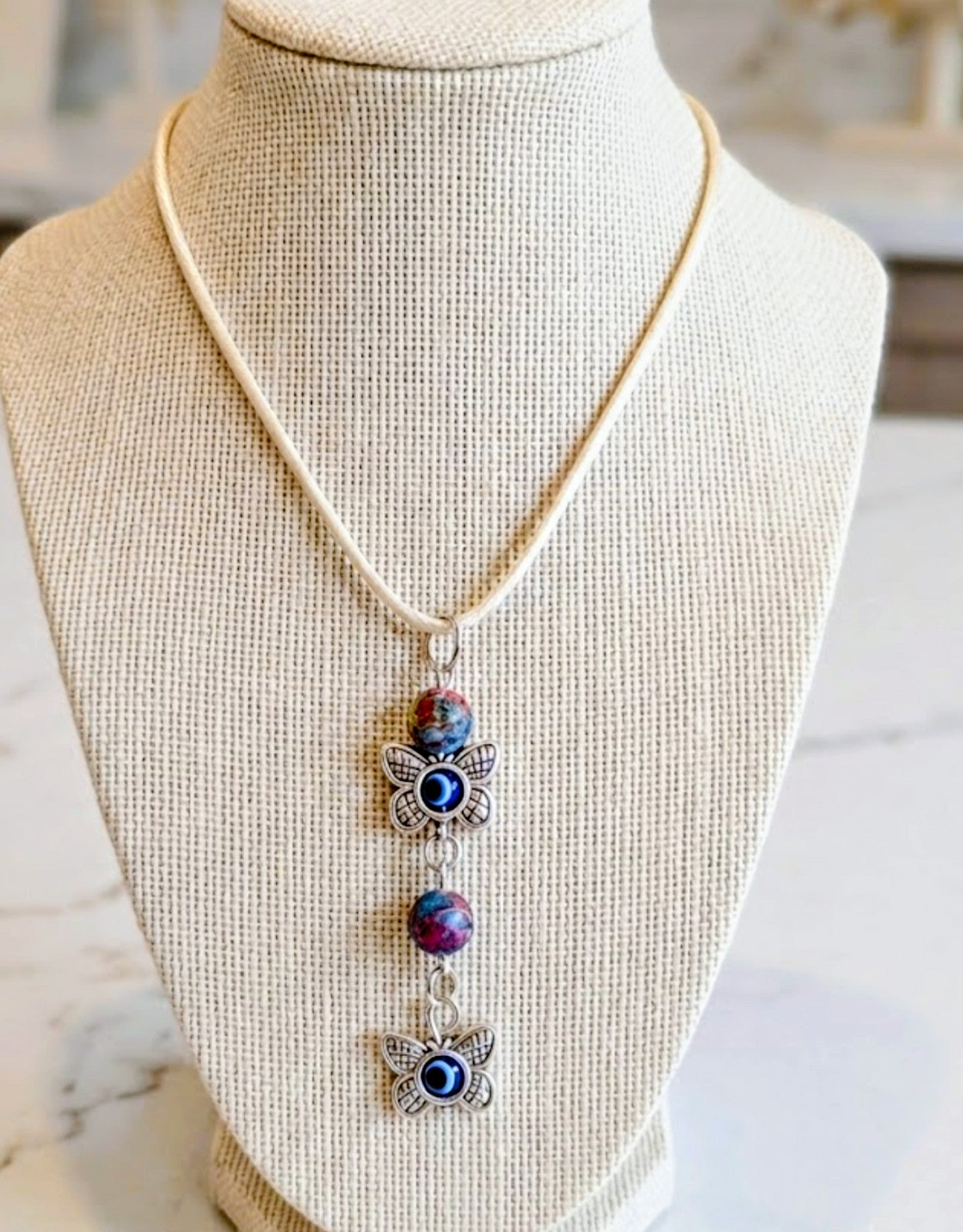 Butterfly & Evil Eye Charm Necklace — Multi-Color Beads on Beige Cord